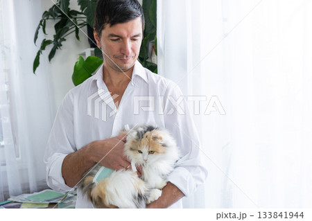 A veterinarian holds a bandaged cat in a blanket after a sterilization operation. 133841944