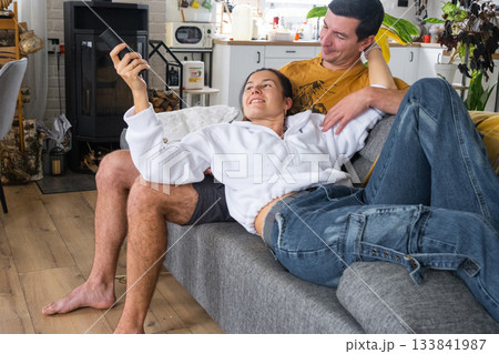 Man and woman at home in a white interior sits on the couch and watches TV, black screen mock up. Home recreation, leisure, love, family, date 133841987