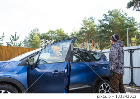 The woman gets behind the wheel, Husband and wife get into the car near the house in the yard The woman gets behind the wheel, Husband and wife get into the car near the house in the yard 133842012