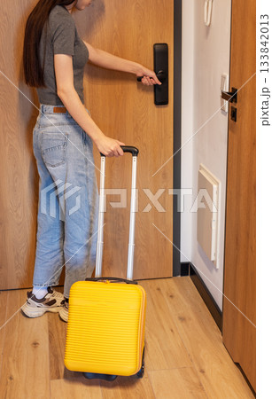 Woman with luggage opening hotel room door Woman with luggage opening hotel room door 133842013