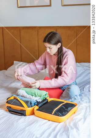 Woman packing suitcase on bed for travel vacation 133842020