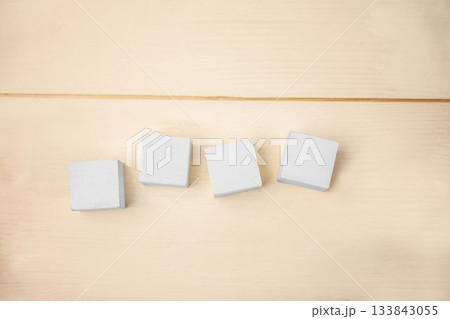 Flat wood tabletop is showing four rotating white square blocks over grain lines in flat design 133843055