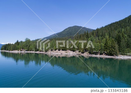 Forest on mountain by river against blue sky Forest on mountain by river against blue sky 133843186