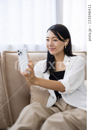 スマートフォンを持ち笑顔で手を振る女性 133846411