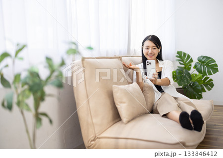 スマートフォンを持ち笑顔で手を振る女性 スマートフォンを持ち笑顔で手を振る女性 133846412
