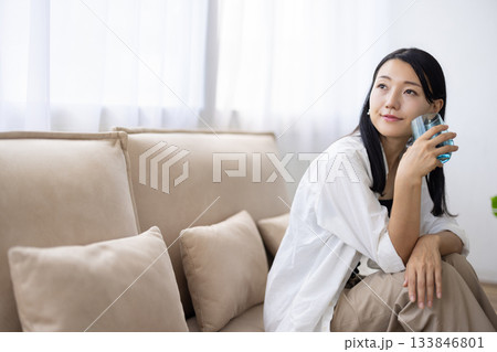水の入ったグラスを持って微笑む女性 133846801