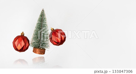 Christmas gray background with green tree and red Christmas balls flying in the air with reflection. Christmas and New Year design holiday card. Flat lay, copy space 133847306