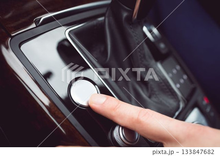 White finger pressing a small white button on a gear shift in a car White finger pressing a small white button on a gear shift in a car 133847682
