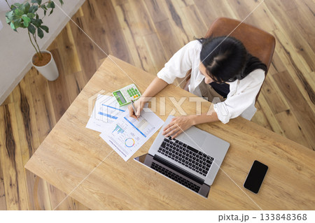 パソコンと資料を広げて作業する女性 133848368