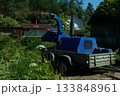 An operator loads tree branches into a wood chipper. 133848961