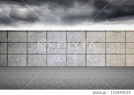 Flat design tiled concrete wall is stretching across open paved ground, with stormy clouds overhead 133849255