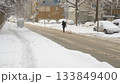 Snowy Urban Street With Person Walking and Pulling Sled 133849400