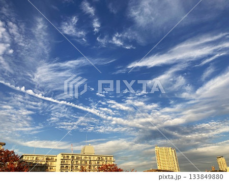 にぎやかな秋の雲を横切る飛行機雲 133849880
