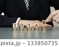business people places a target block on stacks of coins beside number of year 2026 on wooden cubes, symbolizing investment strategy, financial planning, revenue goals, growth, execution, success 133850735
