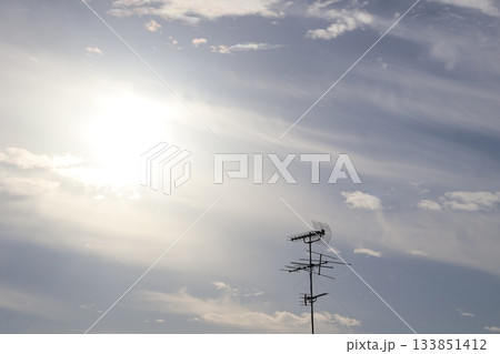 白く光り輝く太陽と薄雲と青空とアンテナの見える風景 白く光り輝く太陽と薄雲と青空とアンテナの見える風景 133851412