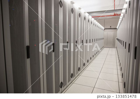 Server cabinets are receding into server room hallway in 3D render with raised floor tiles 133851478