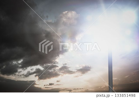 Metal lamp post with glowing fixture is radiating lens flares in flat design under dramatic clouds Metal lamp post with glowing fixture is radiating lens flares in flat design under dramatic clouds 133851498
