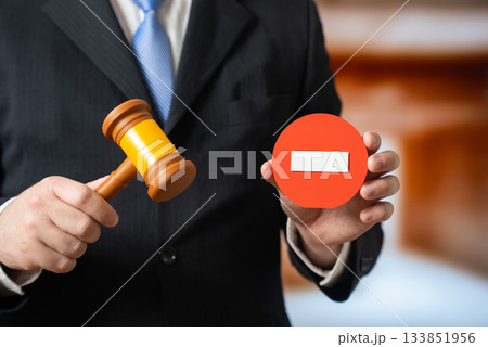 An official with a judge's gavel and a stop sign. New prohibitions and laws. Regulatory updates, compliance notifications and government policy announcements. 133851956