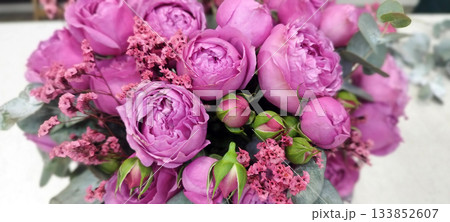 Lush bouquet of vibrant pink peony roses, accented with delicate spray flowers and eucalyptus leaves. The rich texture and soft hues create a romantic and elegant floral arrangement 133852607