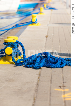 Sailing ropes tied around pins in sunlight 133852911