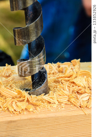 Metal machine drilling in wooden board Metal machine drilling in wooden board 133852926