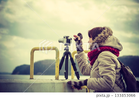 Woman taking pictures on coastline 133853066