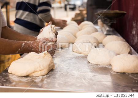 men's hands kneading yeast dough on a bread baking table 133853344