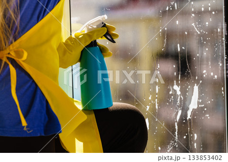 Person spraying window cleaning detergent 133853402