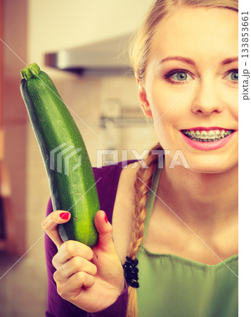 Woman in kitchen holds zucchini vegetable 133853661