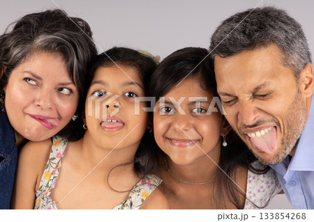 A family of four, including a man and three girls, are posing for a picture 133854268