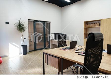 Modern office interior with desktop computers and natural light during the day 133854716
