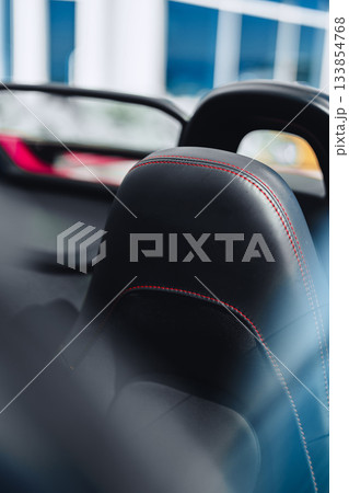 Stylish car interior featuring a black leather seat with red stitching 133854768