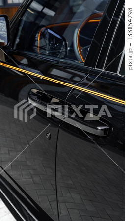 Close-up of a sleek black car door with a modern handle and reflective surface details Close-up of a sleek black car door with a modern handle and reflective surface details 133854798