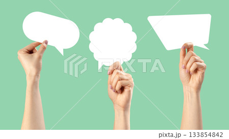 Creative hands holding empty speech bubbles on a light green background for communication ideas Creative hands holding empty speech bubbles on a light green background for communication ideas 133854842