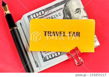 A bundle of cash rests beside a pen and a yellow note that reads travel far, inviting dreams of new destinations and thrilling journeys to experience A bundle of cash rests beside a pen and a yellow note that reads travel far, inviting dreams of new destinations and thrilling journeys to experience 133855217