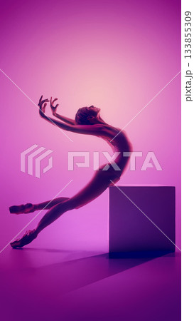 Ballerina arching backward on cube in vivid pink studio glow 133855309