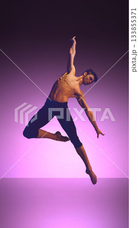 Ballet dancer in expansive high kick with flowing fabric on neon blue-violet stage 133855371