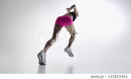 Low-angle view of female athlete sprinting forward in dynamic motion 133855461