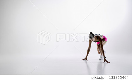 Female athlete stepping into starting position on white background 133855464