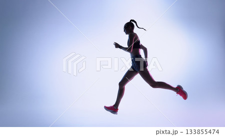 Futuristic female runner moving in dynamic silhouette across neon gradient background Futuristic female runner moving in dynamic silhouette across neon gradient background 133855474