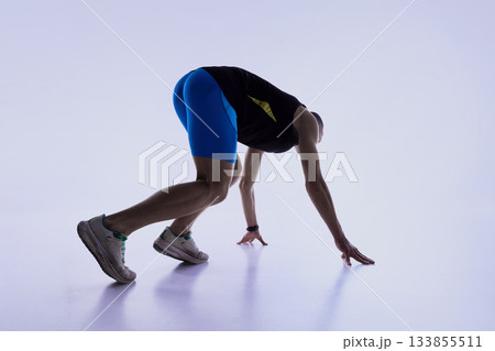 Athlete bending low into deep start setup. 133855511