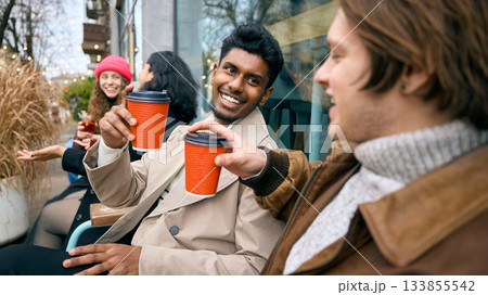 Young men toasting takeaway drinks during cold season hangout 133855542