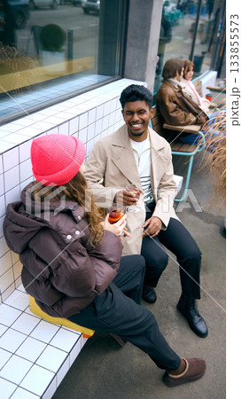 Friends enjoying warm drinks outside city cafe in winter. 133855573