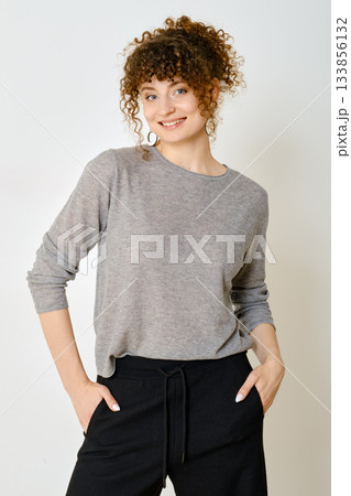 Young woman wearing casual outfit and smiling confidently in a well-lit indoor setting Young woman wearing casual outfit and smiling confidently in a well-lit indoor setting 133856132