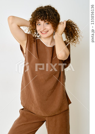 Model showcases stylish brown outfit with playful hairstyle in a bright indoor setting 133856136