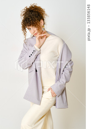 Stylish woman in a light jacket posing confidently against a plain background Stylish woman in a light jacket posing confidently against a plain background 133856148