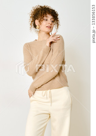 Model poses in casual outfit showcasing cozy sweater and relaxed pants indoors Model poses in casual outfit showcasing cozy sweater and relaxed pants indoors 133856153