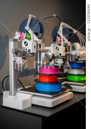 row of colorful 3d printing filament PLA material on environmentally friendly and recyclable paper cardboard spools on black carbon fiber background. modern FDM printer technology concept row of colorful 3d printing filament PLA material on environmentally friendly and recyclable paper cardboard spools on black carbon fiber background. modern FDM printer technology concept 133856844