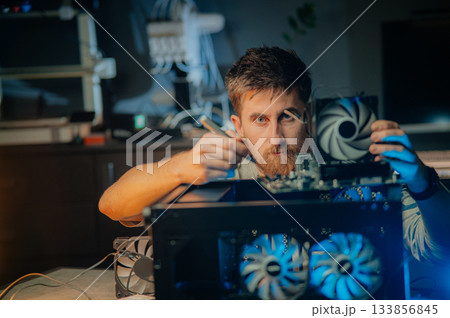 Man assembles a computer system unit at home Man assembles a computer system unit at home 133856845