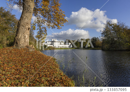 Autumn view of Soestdijk Palace reflecting in the peaceful waters of the pond in Baarn, Netherlands, surrounded by colorful foliage 133857095